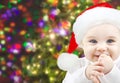 Happy baby in santa hat over christmas lights Royalty Free Stock Photo