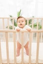 Happy baby girl six months standing in the crib Royalty Free Stock Photo