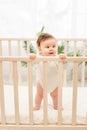 Happy baby girl six months standing in the crib Royalty Free Stock Photo