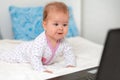 Happy baby in sliders is lying on the bed and watching cartoons on a laptop. The concept of entertainment and education Royalty Free Stock Photo