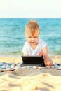 Happy baby with tablet pc on beach. Royalty Free Stock Photo