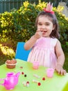 Happy baby toddler girl, eating gummies laughing and smiling in outdoor tea party Royalty Free Stock Photo