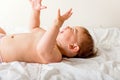 Happy baby toddler laying on the white bedding and smiling. Top view. Happy child Royalty Free Stock Photo