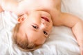 Happy baby toddler laying on the white bedding and smiling. Top view. Happy child Royalty Free Stock Photo