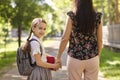 Happy back to school. Back view of mother and cute daughter holding hand while walking to school along city street. Royalty Free Stock Photo