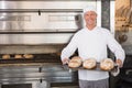 Happy baker holding tray of fresh bread Royalty Free Stock Photo