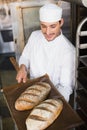 Happy baker holding tray of fresh bread Royalty Free Stock Photo