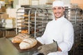 Happy baker holding tray of fresh bread