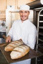 Happy baker holding tray of fresh bread Royalty Free Stock Photo