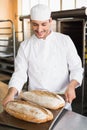 Happy baker holding tray of fresh bread Royalty Free Stock Photo