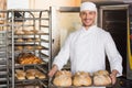 Happy baker showing tray of fresh bread Royalty Free Stock Photo