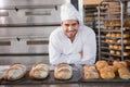 Happy baker standing near tray with bread Royalty Free Stock Photo