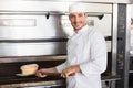 Happy baker taking out fresh loaf Royalty Free Stock Photo