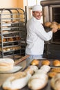 Happy baker taking out fresh loaves Royalty Free Stock Photo