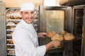 Happy baker taking out fresh loaves Royalty Free Stock Photo