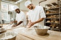 happy bakers kneading dough together at baking manufacture