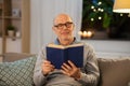 Happy bald senior man on sofa reading book at home Royalty Free Stock Photo