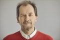 Portrait of happy balding senior man looking at camera on grey studio background