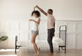 Happy barefoot african american loving family couple dancing in bedroom.