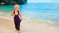 Happy barefoot child in loose jumpsuit on tropical sea beach