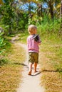 Happy barefoot child walk alone on beach by jungle path