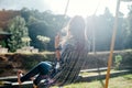 Happy barefoot girl on swing in sun light