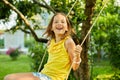 Happy barefoot laughing child girl swinging on a swing in sunset summer day Royalty Free Stock Photo