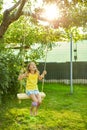 Happy barefoot laughing child girl swinging on a swing in sunset summer day Royalty Free Stock Photo