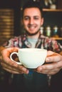 Happy barista offering cup of coffee to camera Royalty Free Stock Photo