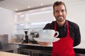 Happy barista offering cup of coffee to camera Royalty Free Stock Photo