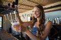 Happy barmaid pouring beer from tap in glass Royalty Free Stock Photo