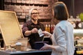 Happy barman and woman paying money at cafe