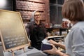 Happy barman and woman paying money at cafe