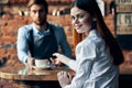 happy bartender serving a cup of coffee to a patient in a cafe drink brick wall interior