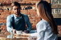 happy bartender serving a cup of coffee to a patient in a cafe drink brick wall interior