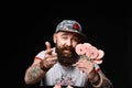 Happy bearded brutal man in a fashionable cap holds a pack of lollipops candies