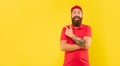 Happy bearded guy in casual red cap and tshirt pointing finger aside copy space, advertise Royalty Free Stock Photo