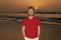 happy bearded handsome man in summer shirt on beach with sunset over sea, summer Royalty Free Stock Photo