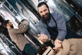 Happy bearded man in apron pours barley into hand of craft brewery. Process of beer manufacturing.