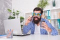 Happy bearded man in cool glasses drink coffee talking on mobile phone in modern office, addiction