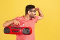 Happy bearded man in eyeglasses and striped t-shirt looking far away holding hand above forehead and holding retro tape recorder, Royalty Free Stock Photo