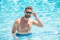 happy bearded man in glasses swimming in pool on summer, relax