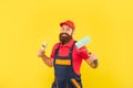 happy bearded man painter in work clothes hold paint roller and brush on yellow background Royalty Free Stock Photo