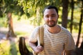 Happy bearded man traveler with backpack walking in forest. Tourism, travel, adventure, hike concept - smiling young man