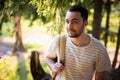 Happy bearded man traveler with backpack walking in forest. Tourism, travel, adventure, hike concept - smiling young man