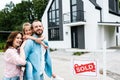 Bearded man piggybacking daughter near cheerful wife and board with sold letters