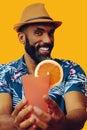 happy bearded mid adult african american man wearing Hawaiian shirt and hat smiling offering orange juice cocktail at