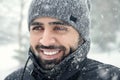Happy bearded Middle eastern man wearing winter clothes under the snow