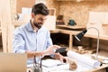 Happy bearded timber craftsman using modern gadget in his work