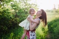 Happy beatiful Mom kisses and hugs daughter on nature in sunset light